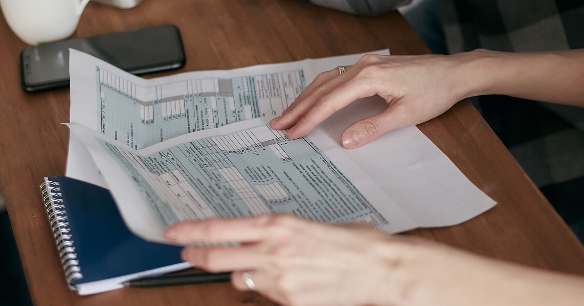 Two people reviewing medical billing paperwork at a table with a calculator